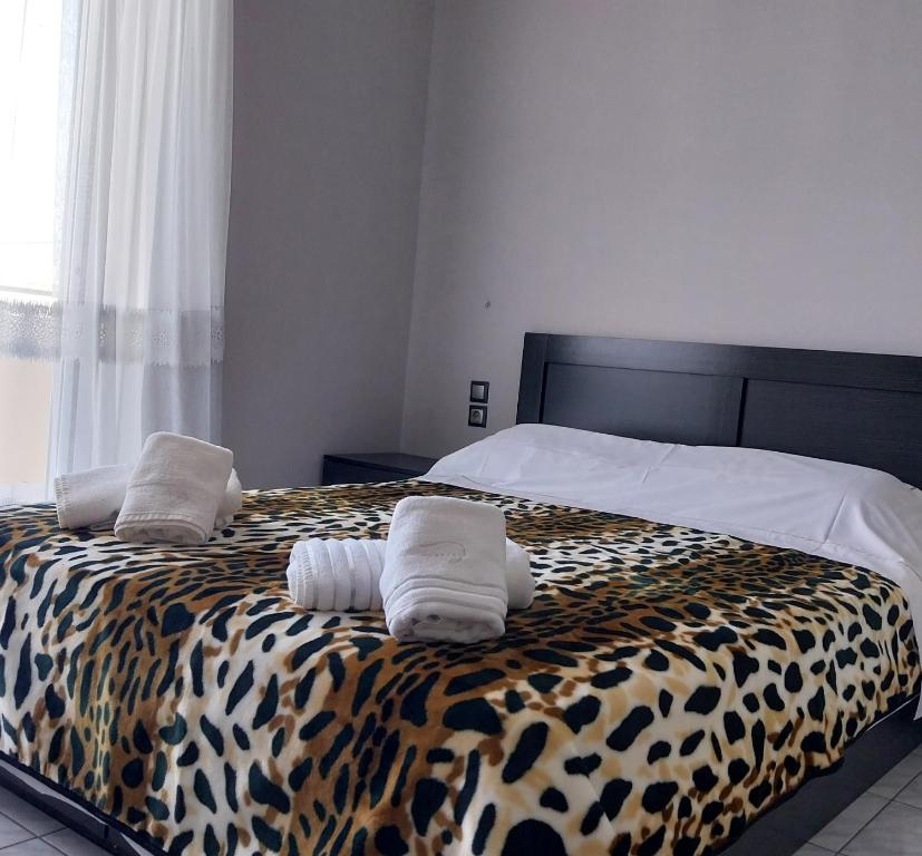Una cama con estampado de guepardo con dos toallas. en SWEET APPARTMENT, en Patra