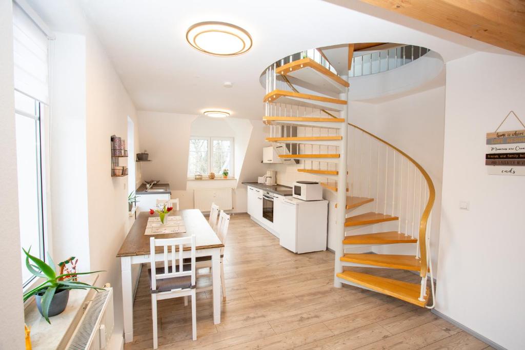 eine Küche und ein Esszimmer mit einer Wendeltreppe in einem winzigen Haus in der Unterkunft Ferienwohnung Zschopau Zentrum in Zschopau