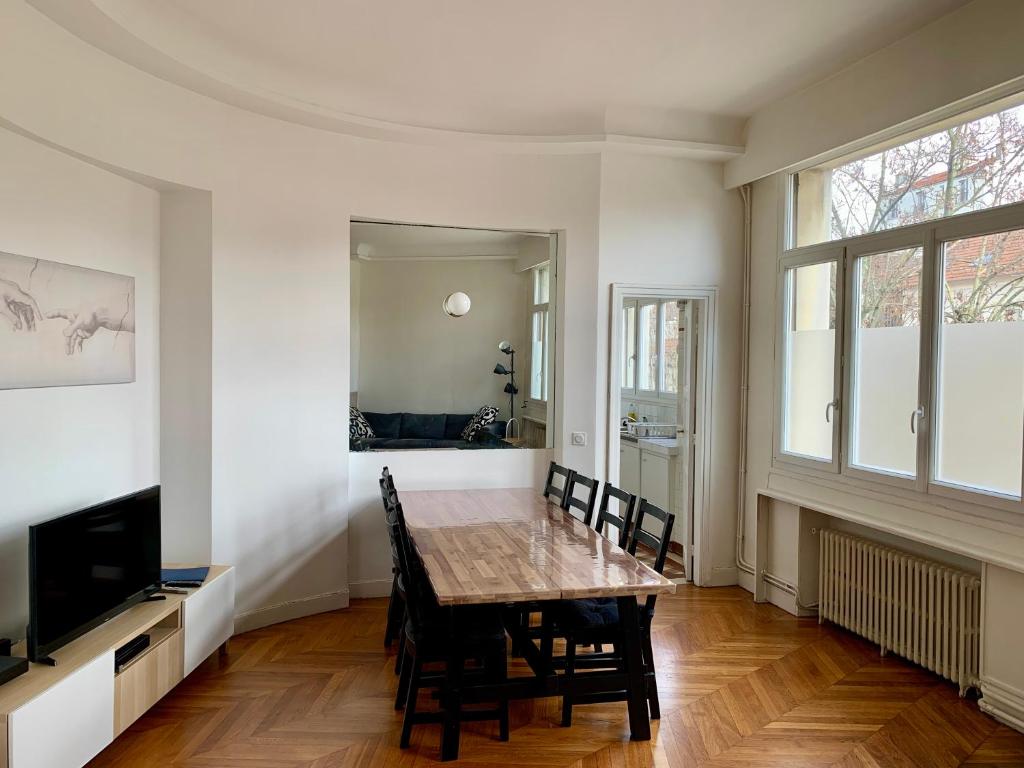 Paris Apartment 5-minute walk to tube station في ليه ليلاس: غرفة طعام مع طاولة وكراسي وتلفزيون