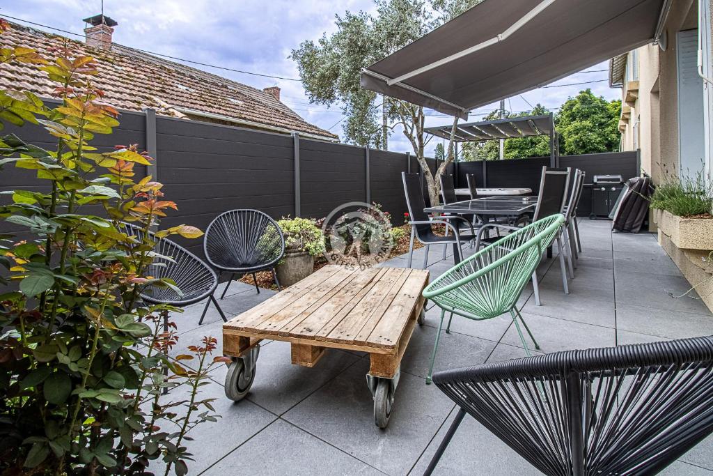 un patio avec une table, des chaises et un parasol dans l'établissement Location appartement des Pyrénées, à Bordères-sur-lʼÉchez