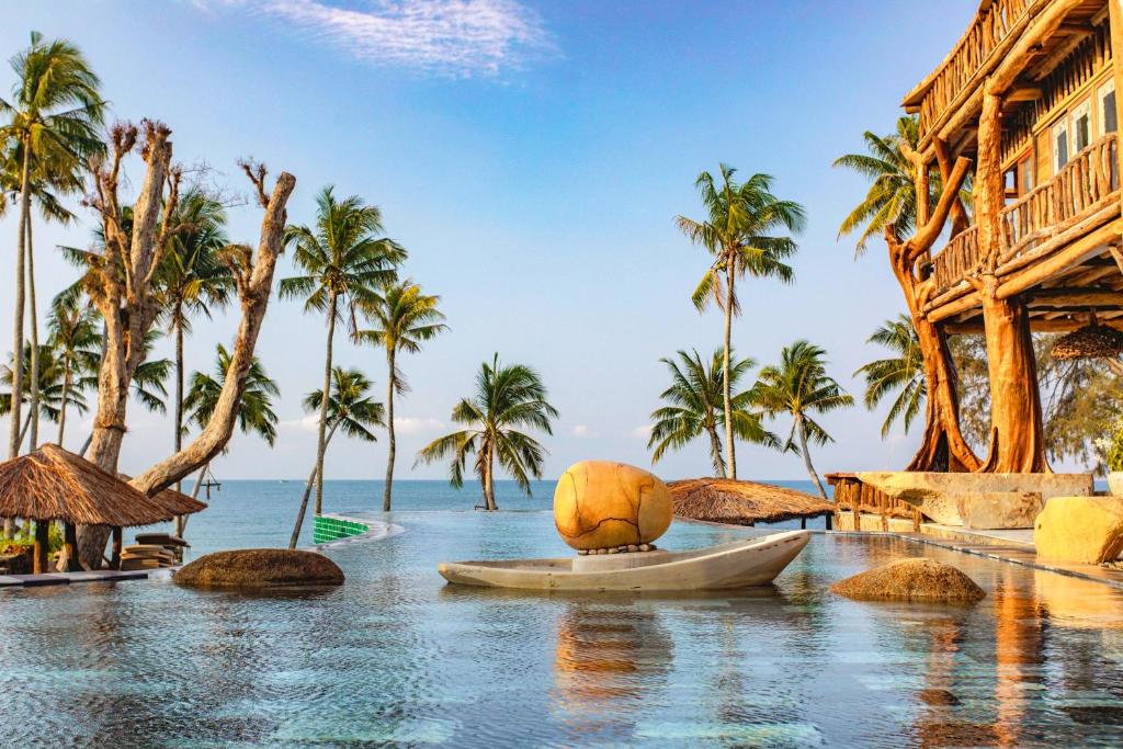a resort with palm trees and a boat in the water at GRAND OCEAN BAY RESORT PHU QUOC in Phu Quoc