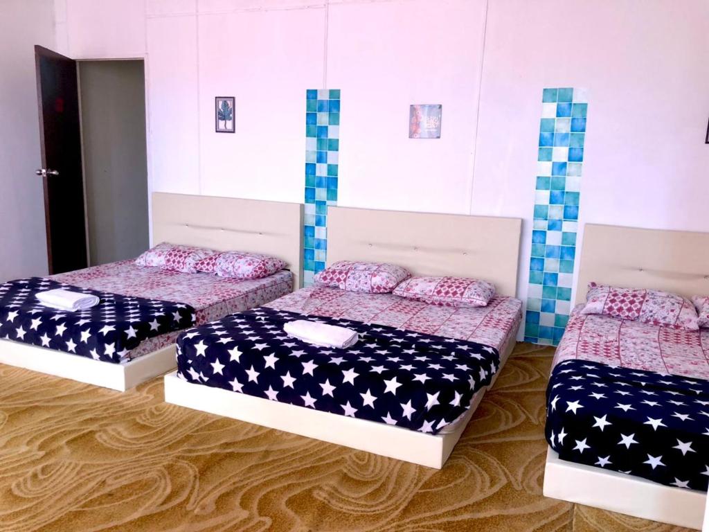 drie bedden in een kamer met sterren en strepen bij Alia Express CZ Hotel in Pasir Puteh
