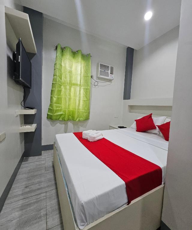 a bedroom with a bed with red and green sheets at JRJA Suites 1 near Card Bank Tagum in Tagum