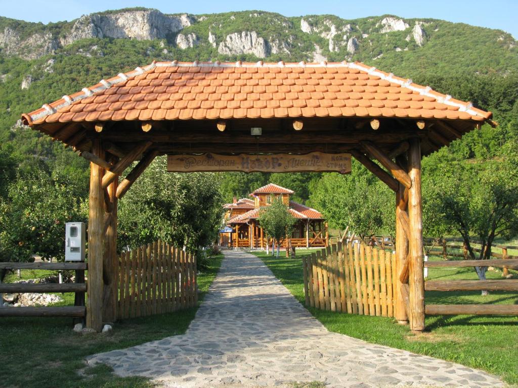 a wooden gazebo with a fence and a house at Apartments Izvor Lisine in Strmosten