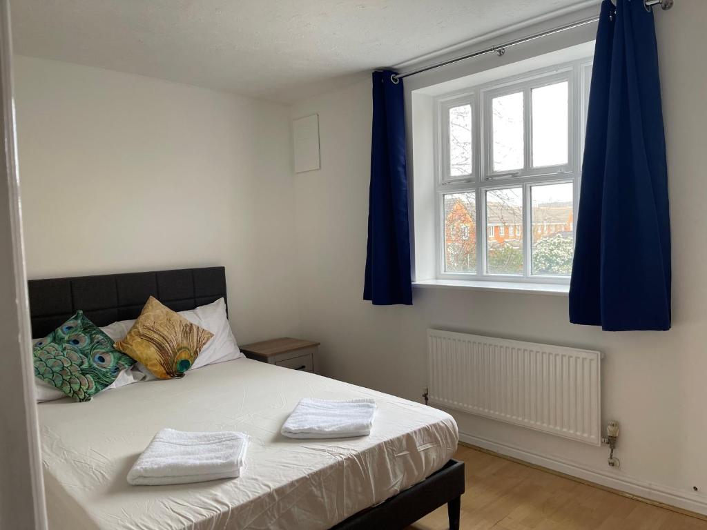 a bedroom with a bed with blue curtains and a window at 2Bed Cozy Spacious apartment - 15min to Canary Wharf O2 Excel Central London in London