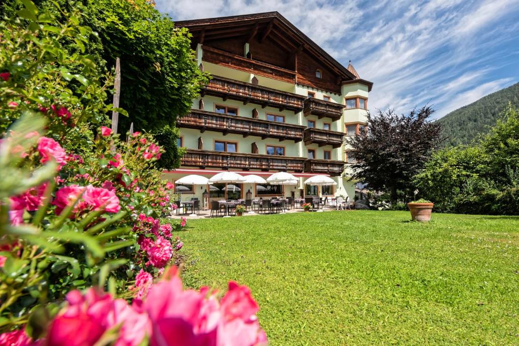 um grande edifício com flores em frente em Das Posthaus stubai&smart Hotel em Fulpmes