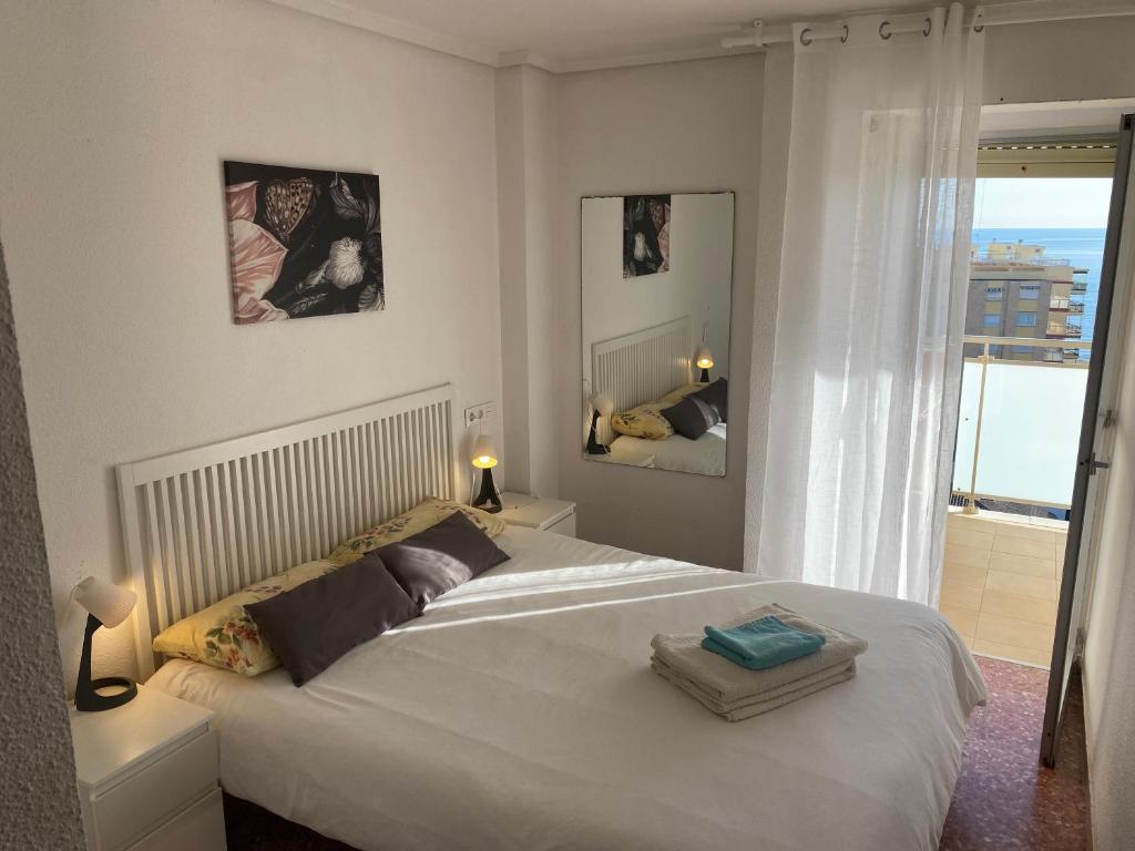 a bedroom with a large white bed and a balcony at High-Floor Bright Apartment with Sea Views in Mareny Blau