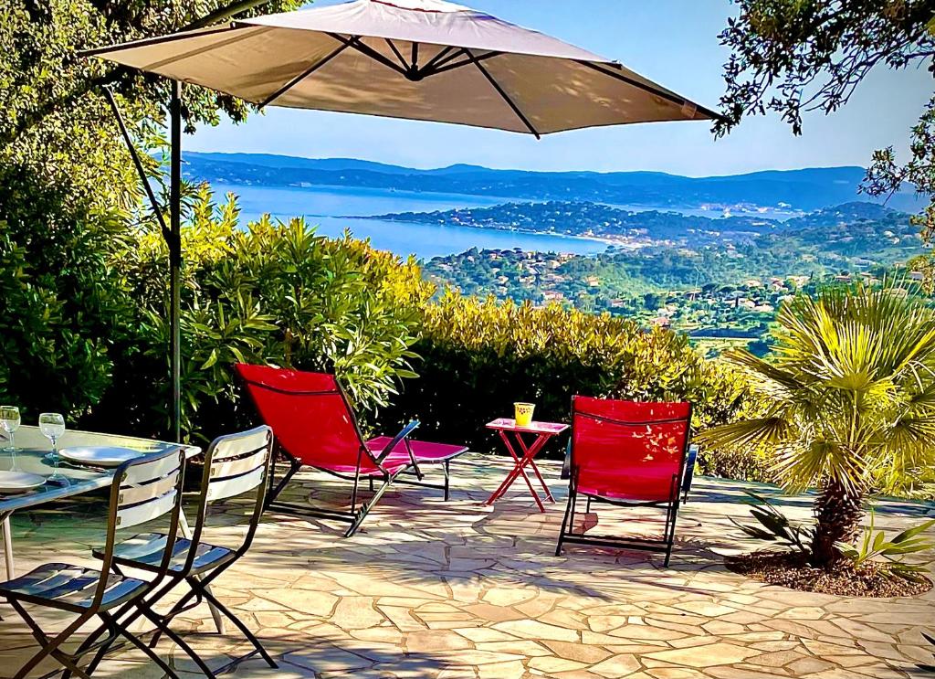 eine Terrasse mit einem Tisch, Stühlen und einem Sonnenschirm in der Unterkunft Loucasa in Roquebrune-sur-Argens