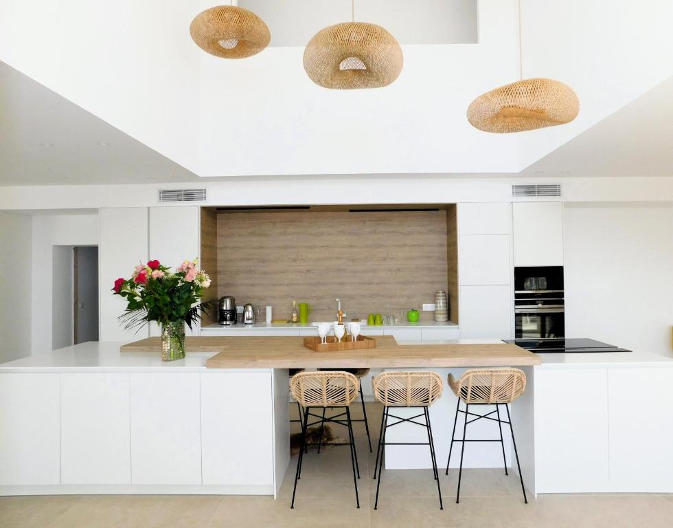 a kitchen with white cabinets and a island with stools at Villa d'exception piscine privée et vue mer in Saint-Cyr-sur-Mer