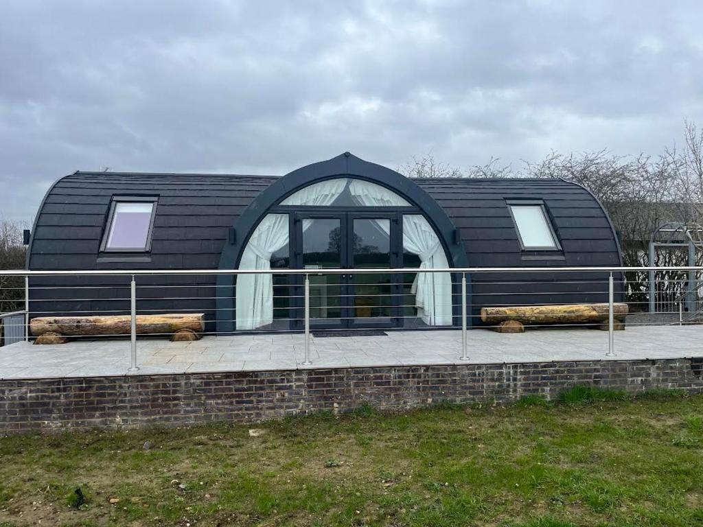 a black house with a black roof and a fence at The Pod @ Cold Comfort Farm in Hinckley