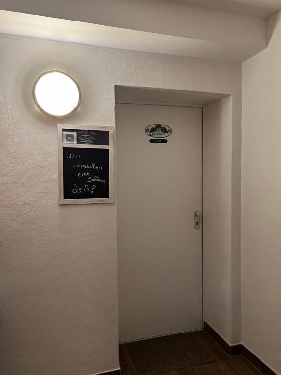 einen Flur mit einer Tür mit einer Tafel und einer Lampe in der Unterkunft Elpe in Olsberg