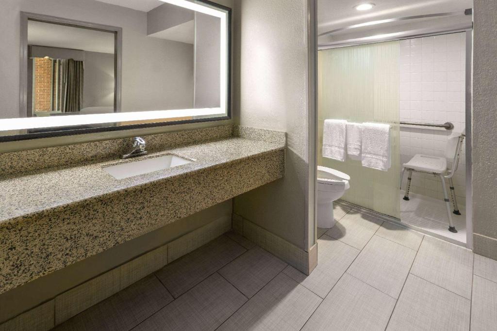 a bathroom with a sink and a toilet and a mirror at Days Inn by Wyndham Forsyth in Forsyth