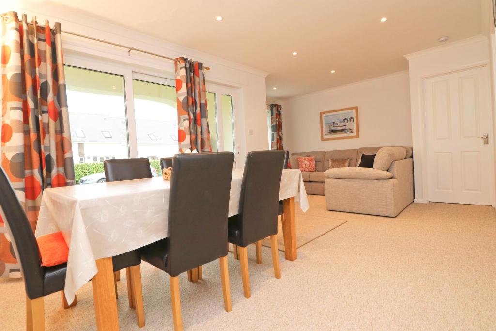 a dining room with a table and chairs and a couch at 7 BAYS for 7 DAYS! Spacious bungalow near 7 beaches in St Merryn