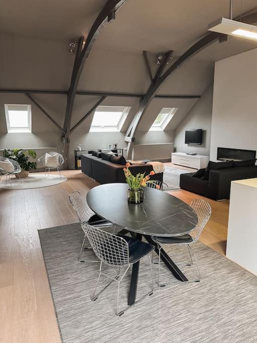 Loft @ de Vlaamse Ardennen في براكيل: غرفة معيشة مع طاولة سوداء وكراسي