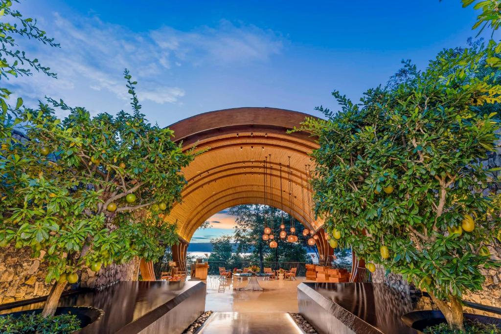 a building with an arch with trees and tables at Andaz Costa Rica Resort at Peninsula Papagayo – A concept by Hyatt in Papagayo, Guanacaste