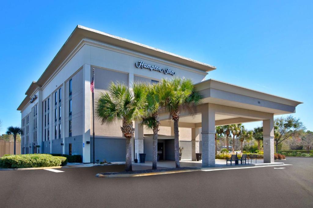 a building with palm trees in a parking lot at Hampton Inn Daytona/Ormond Beach in Ormond Beach