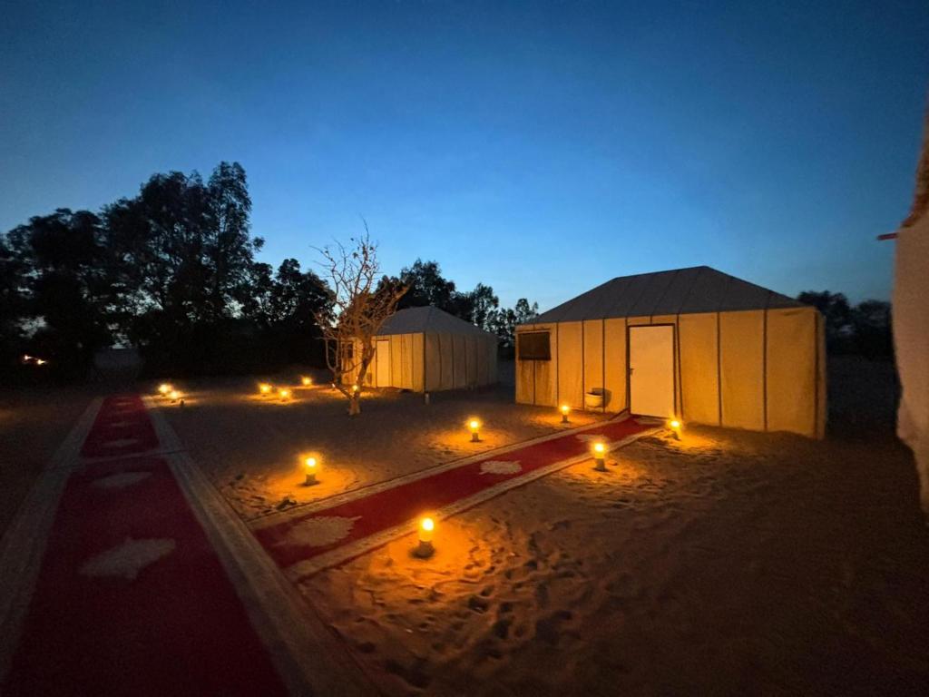 a building with lights in the sand at night at Shooting Stars Camp in Merzouga
