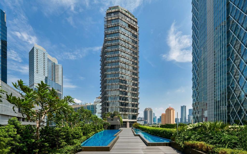 a tall building with a swimming pool in a city at Alila SCBD Jakarta in Jakarta