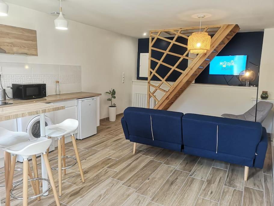 ein Wohnzimmer mit einem blauen Sofa und einer Küche in der Unterkunft La Bohème - Maison + Parking (Portes de Chartres) in Jouy