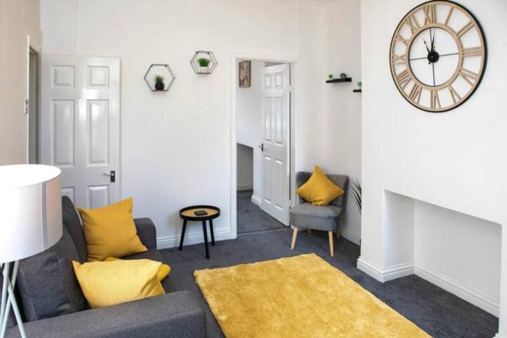 un soggiorno con divano e orologio sul muro di Cosy Three-Bedroom Willow House a Selby