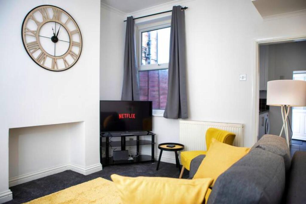 - un salon avec un canapé et un réveil sur le mur dans l'établissement Cosy Three Bedroom Willow House, à Selby