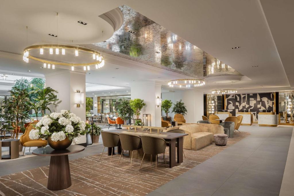 a lobby with a waiting area with tables and chairs at Hilton Heidelberg in Heidelberg