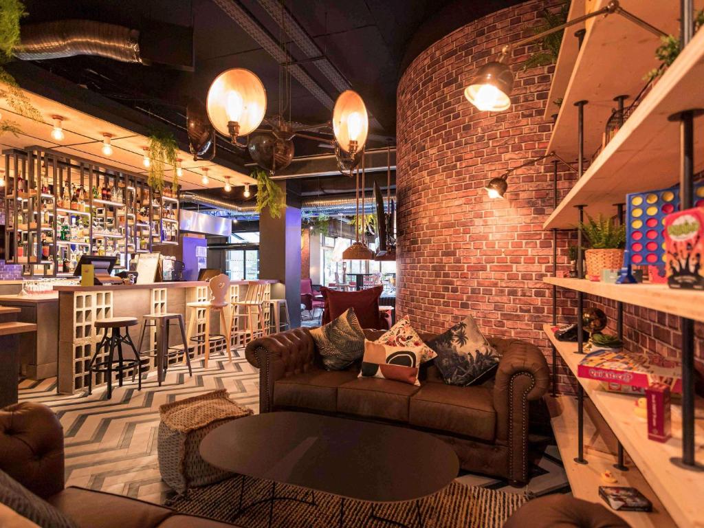 a living room with a couch and a brick wall at ibis Styles Strasbourg Nord Palais des Congr&egrave;s in Schiltigheim