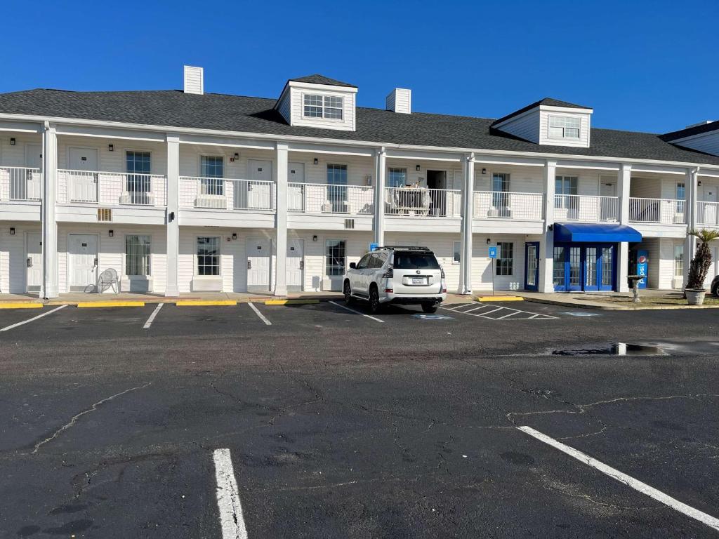 un coche blanco estacionado en un estacionamiento frente a un edificio en Motel 6 Georgetown, SC Marina en Georgetown