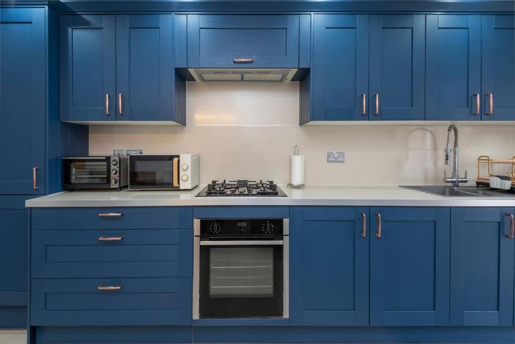 cocina azul con armarios azules y microondas en Stunning 3-Bed House, en Londres