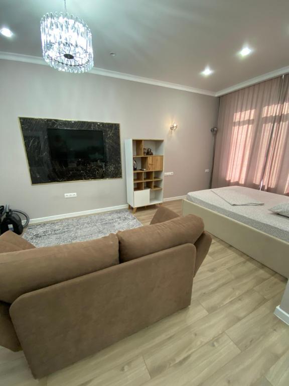 a living room with a couch and a bed at Однокомнатные бизнес апартаменты в ЖК Заман in Atyraū