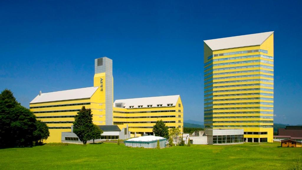 tres edificios altos de color amarillo con un campo verde delante en ANA Crowne Plaza Resort Appi Kogen, an IHG Hotel, en Hachimantai