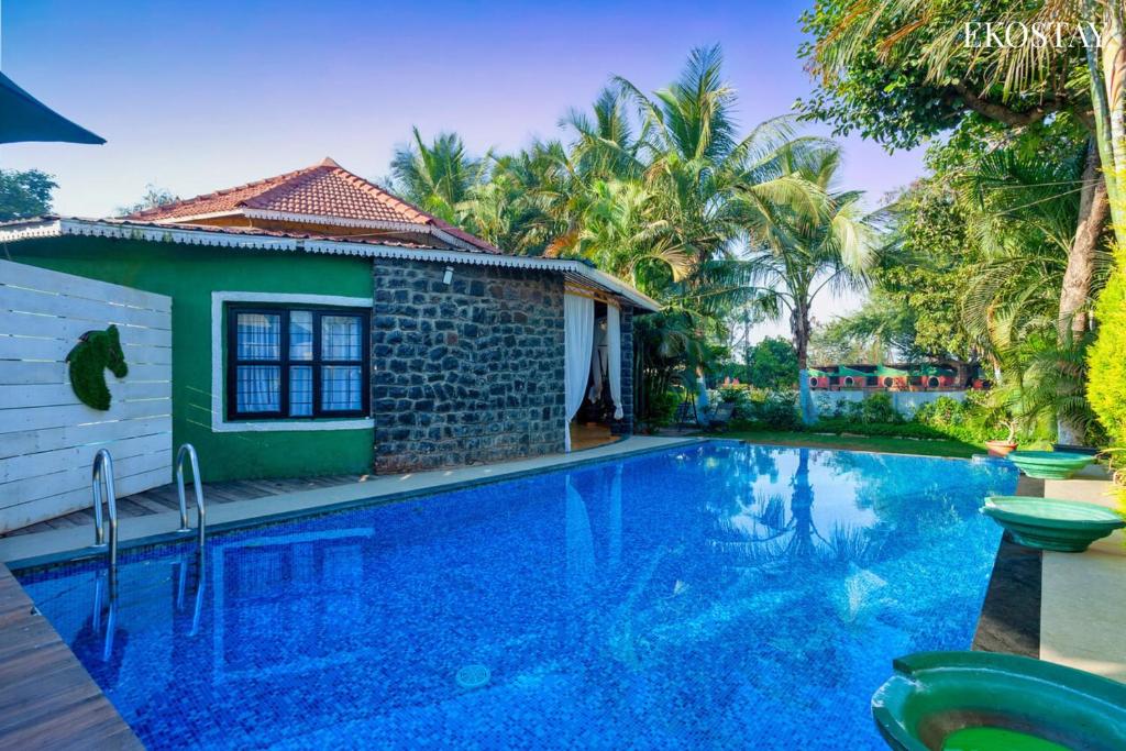 a villa with a swimming pool in front of a house at EKO STAY - The Ranch Villa in Deolāli