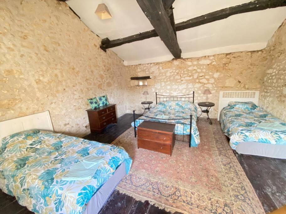 een slaapkamer met 2 bedden, een dressoir en een tafel bij Maison du 12ème siècle in Saint-Privat-des-Prés