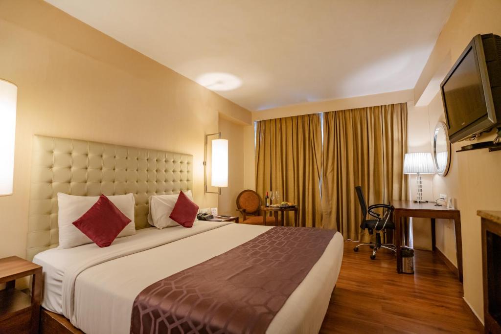 Pokój hotelowy z dużym łóżkiem i telewizorem w obiekcie Royal Orchid Central Jaipur, Bani Park w mieście Dżajpur