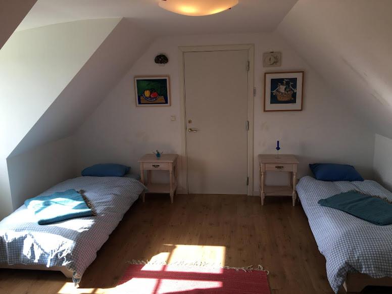 a attic room with two beds and two tables at Gladsax Gamla Gård in Simrishamn