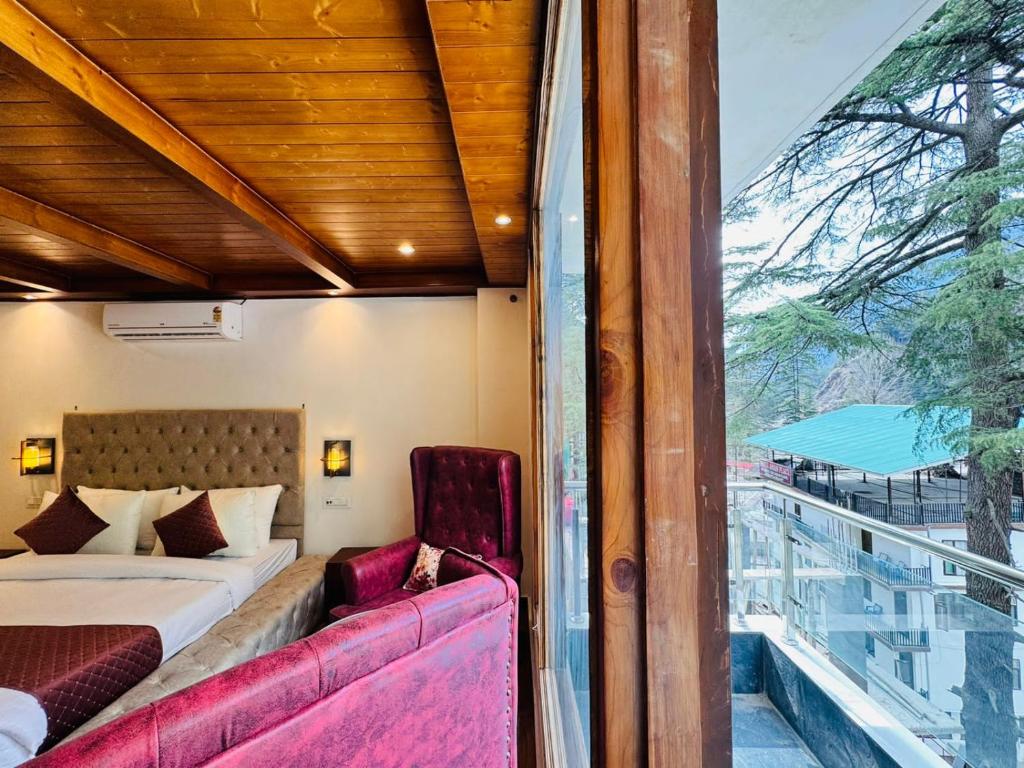 a bedroom with a bed and a balcony with a window at The Kasol Parvati View by - ASIA HOLIDAYS in Kasol