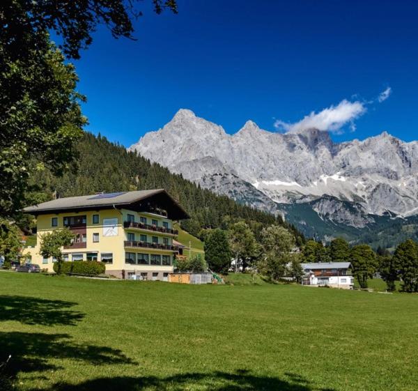 a house in a field with mountains in the background at Hotel Bergglück in Filzmoos