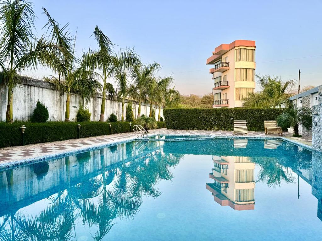 uma piscina com palmeiras e um edifício em Sumedha Resort & SPA Rishikesh em Rishikesh