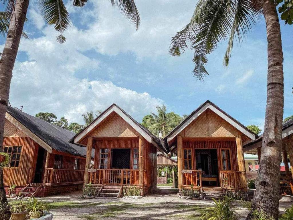 a house with palm trees in front of it at Hola Beach Resort in Siquijor