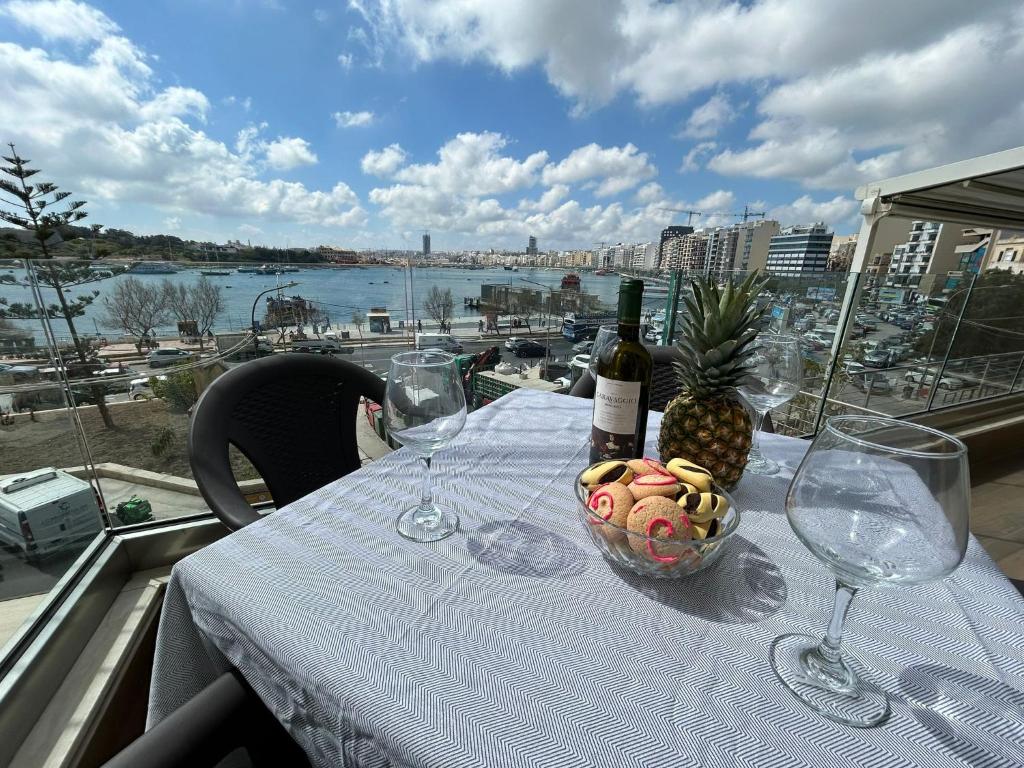 a table with glasses and a bowl of fruit and a bottle of wine at Seaview Serenity 3-Bedroom Apt view over Valletta Harbour in Sliema