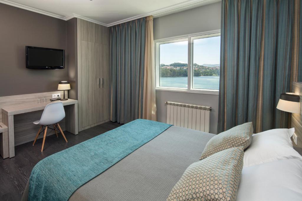 um quarto de hotel com uma cama e uma janela em Hotel Combarro em Combarro
