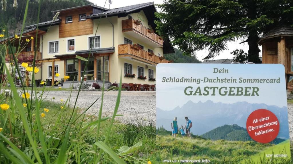 un panneau dans l'herbe devant une maison dans l'établissement Familien & Wander-Pension Purkhardt, à Donnersbachwald