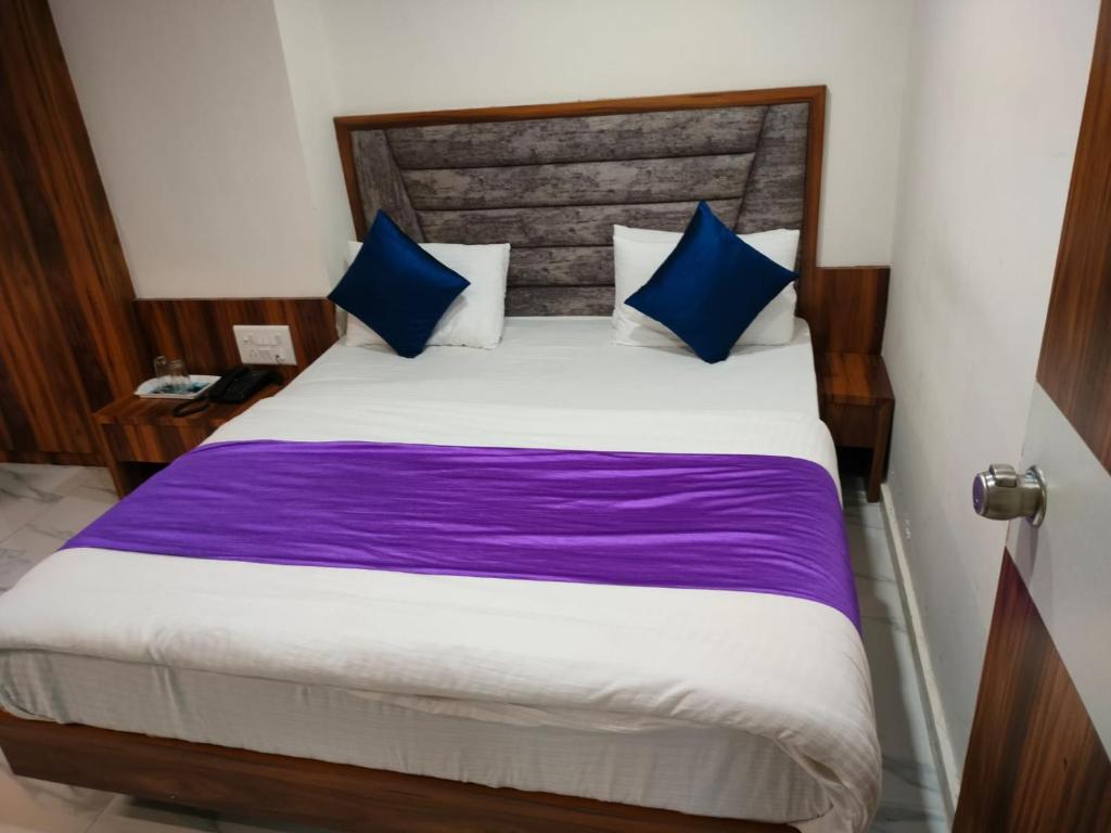 a bedroom with a large bed with blue pillows at Hotel Angell Park in Ahmedabad