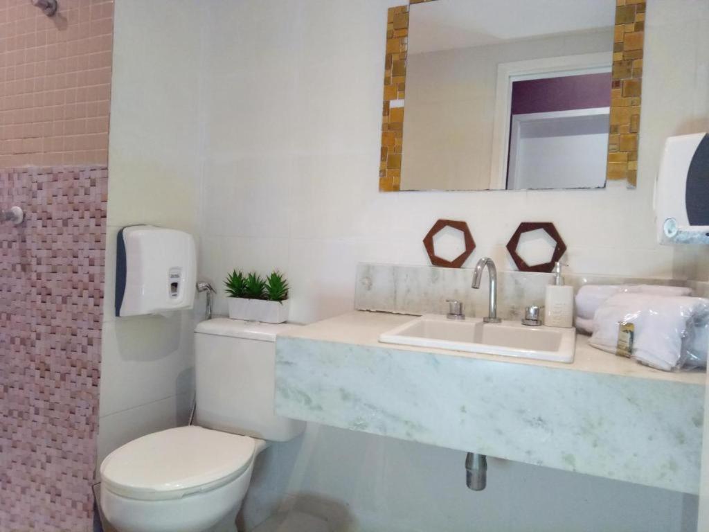 a bathroom with a sink and a toilet and a mirror at Neolink Barra da Tijuca in Rio de Janeiro