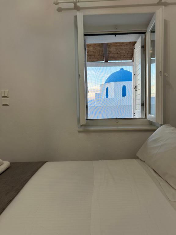 1 dormitorio con 1 cama y ventana con un edificio azul en Harry’s studio, en Naousa