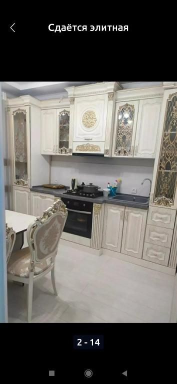 a kitchen with white cabinets and a table and a chair at 1 комнатная квартира in Bishkek