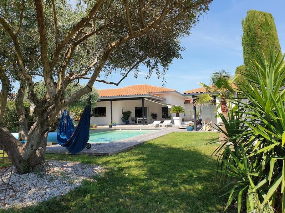 a house with a yard with a hammock next to a pool at Belle villa, piscine et cigales au calme ! in Saint-Jean-de-Védas