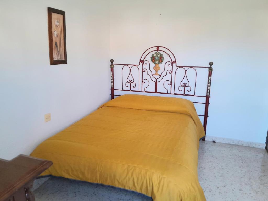 Una cama en una habitación con una manta amarilla. en Room in Shared apartment with Parking, en Almuñécar