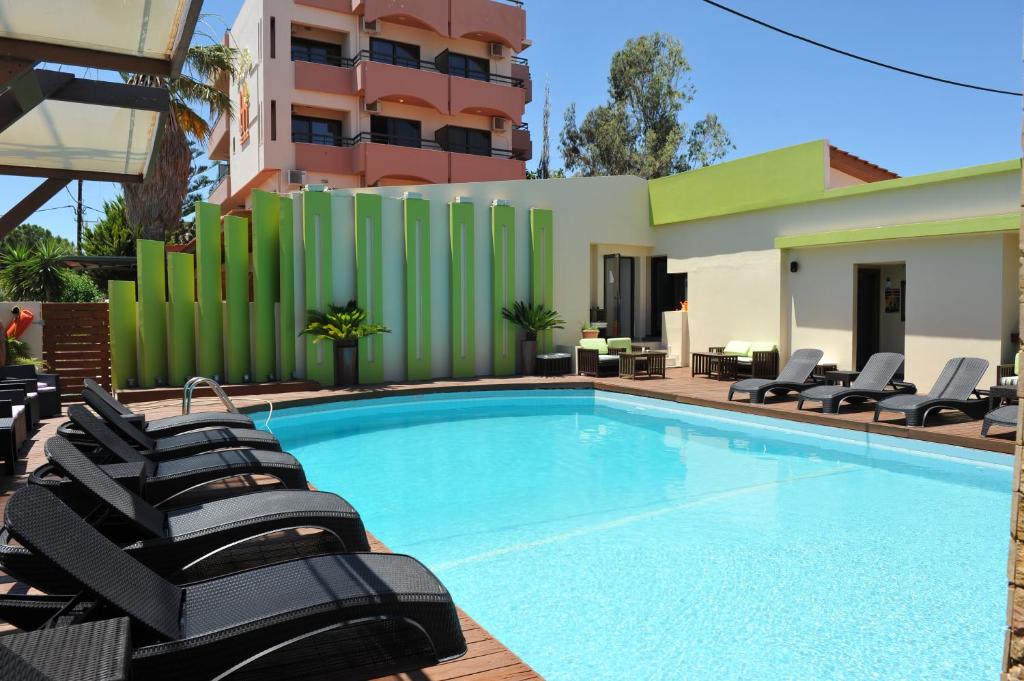 a swimming pool with lounge chairs next to a building at Heleni Beach Hotel in Ialyssos