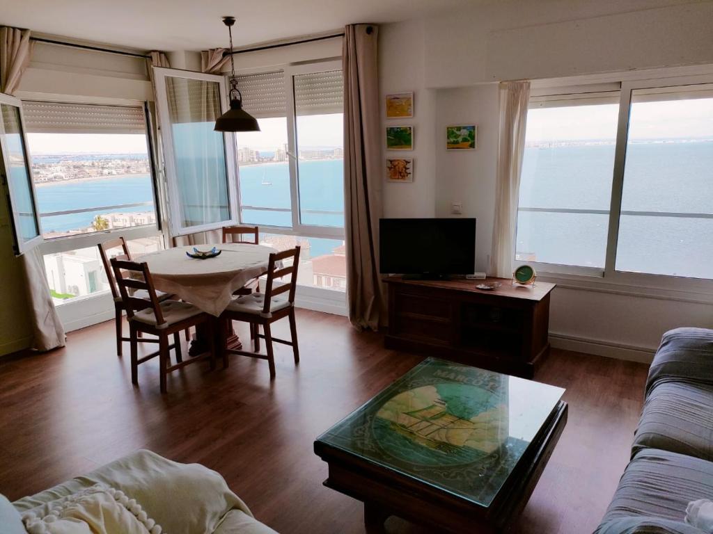 a living room with a table and chairs and a television at Faro Cabo de Palos in Cabo de Palos